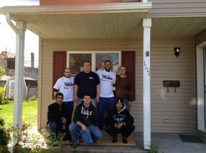 A mix of Penn College students, from English as a Second Language classes and the School of Construction and Design Technologies, stand on the porch of a Habitat for Humanity home.