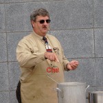 Chef Paul E. Mach gestures toward the soup kettle, where an aromatic blend of ingredients teases his audience.