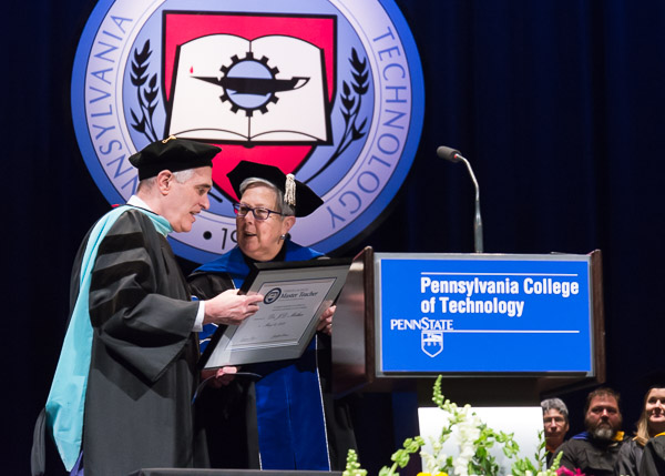 The president presents Mather with his Master Teacher plaque, awarded for only the 31st time in college history.