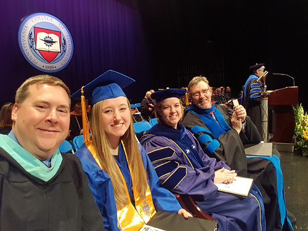 An on-stage selfie showcases members of the platform party. From left are Elliott Strickland, chief student affairs officer; Carts, class representative; Carolyn R. Strickland, vice president for enrollment management/associate provost; and Paul L. Starkey, vice president for academic affairs/provost.