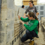 Furnished with trowels and masons' "mud," two Penn State students get to work on laying block.