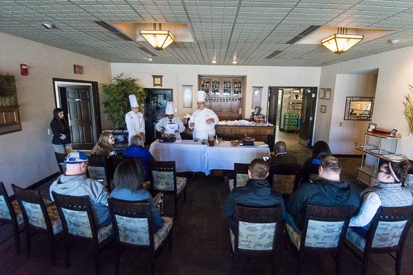 Families learn about the college’s hospitality majors while Chef Paul Mach, assistant professor of hospitality management/culinary arts, calls on the help of a prospective student to demonstrate classical cooking techniques. Also assisting is culinary arts and systems student David O. Spriache, of Reading, left.