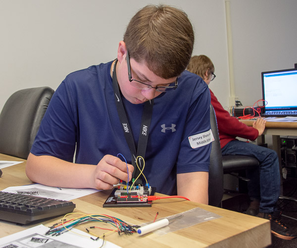 In a session led by Jeff Rankinen, assistant professor of electronics, a Jersey Shore Area Middle School student connects components on an electronic breadboard. They used the circuit boards and software to build a “Simon Says” memory game. LEDS flash a pattern, which the player must remember and repeat using four buttons.