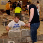 Tape measure at the ready, Andrew R. Hurd, a building construction technology student from Spring Mills, assesses a visitor's block-laying performance.