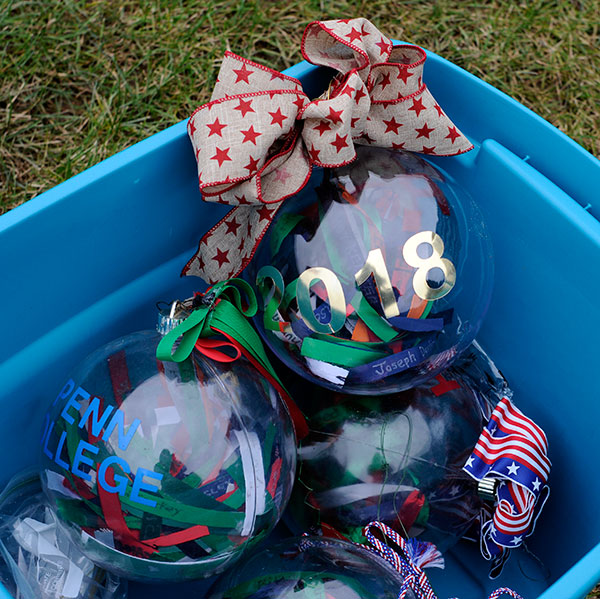 Four glass balls, containing commemorative ribbons bought in an annual Giving Tree benefit for a veterans charity, await placement on the branches.