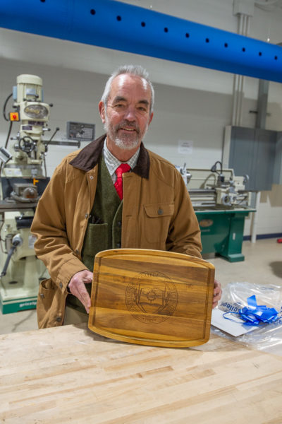 State Rep. Garth Everett displays a cutting board – complete with woodburned college seal – that was presented to each board member.