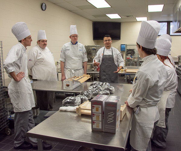 Uribe talks with students while their freshly mixed squid ink pasta dough rests.