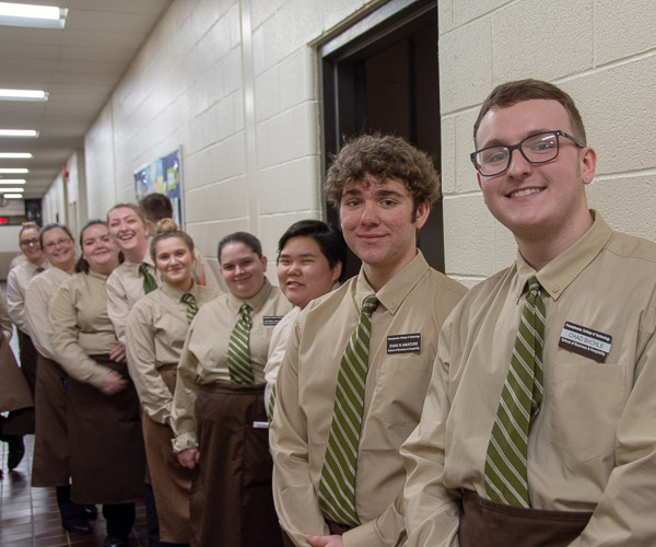 Students acting as servers for the evening indulge a photo while waiting to pick up the next course from the kitchen.