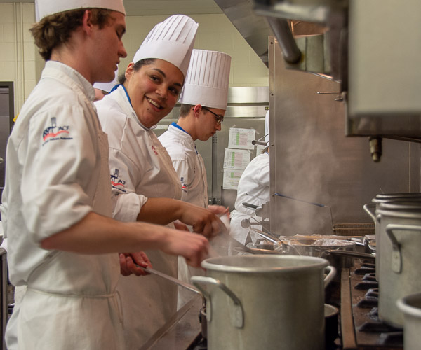 Senior culinary arts and systems students Nolan S. Lester, of Perkiomenville; Amaris T. Smith, of Williamsport; and Jacob W. Parobek, of Seltzer, prepare ingredients for the first course. All three have petitioned to graduate in May.