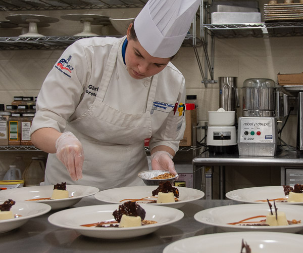 Student Gloria F. Boronow, of Denver, Pa., adds hazelnuts to the dessert.