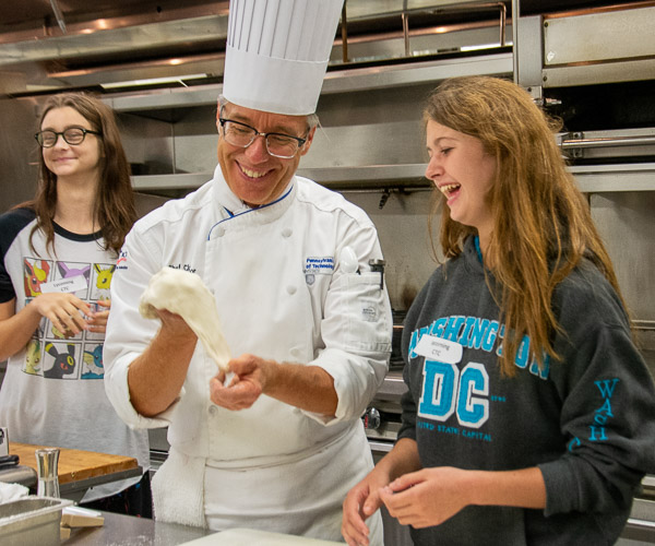 Chef Craig A. Cian, associate professor of hospitality management/culinary arts, helps a student from the Lycoming Career & Technology Center to form pizza dough.