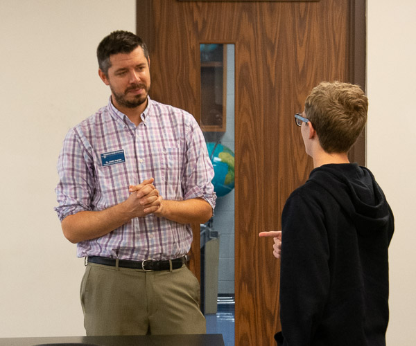 A high school visitor chats briefly with Justin M. Ingram, assistant professor of biology, following Ingram’s session on the science behind brewing and fermentation.