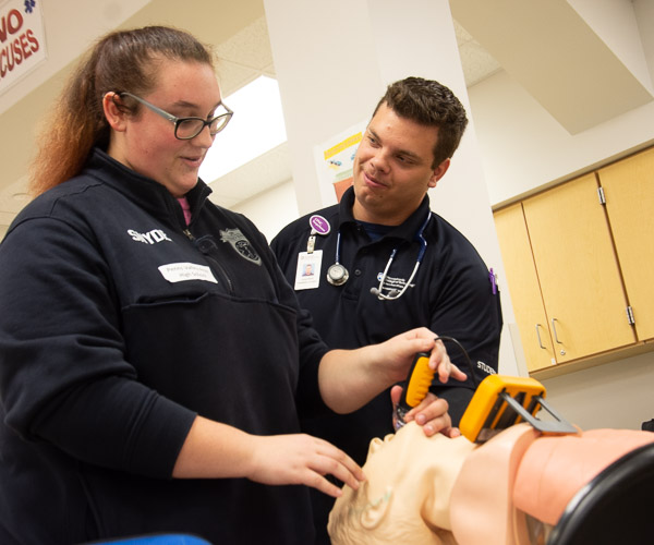 In the paramedic lab, Jaimee C. Moyle (right), an emergency medical services student from Muncy, guides a visitor through placing an airway tube.