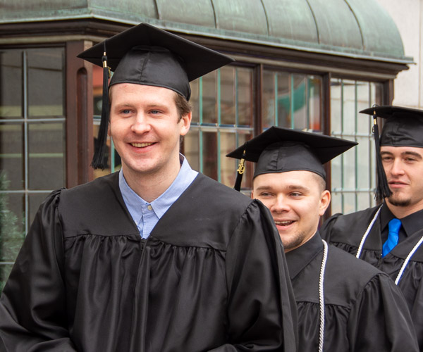 Graduates warm their chilly December procession with smiles.