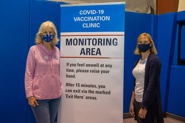 Among those welcoming the convenience of an on-campus clinic are Joanna K. Flynn (left), dean of curriculum and instruction, who also kept traffic moving smoothly, and Barb F. DiMarco, assistant professor of mathematics. 