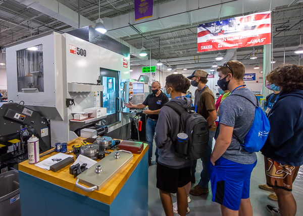 Beneath a banner affirming a beneficial corporate alliance, Richard K. Hendricks Jr., instructor of machine tool technology/automated manufacturing, shows off the newest piece of Haas equipment: a Universal Machining Center that will greatly enhance graduates' marketability.