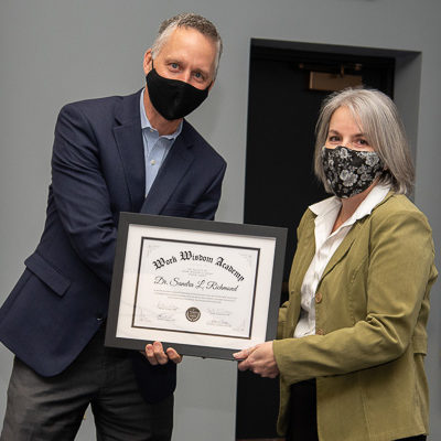 Reed presents a certificate to Richmond, one of the college's three school deans ...