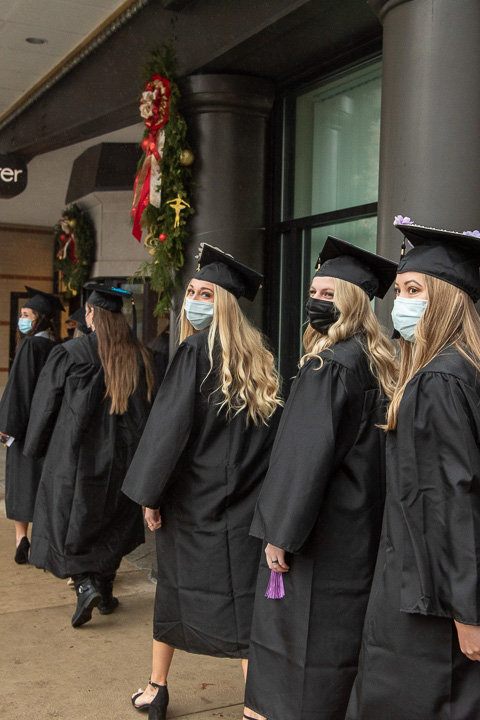 Taking one more look back as they move ahead, students turn to acknowledge the congratulatory honks from cars traveling on West Fourth Street.