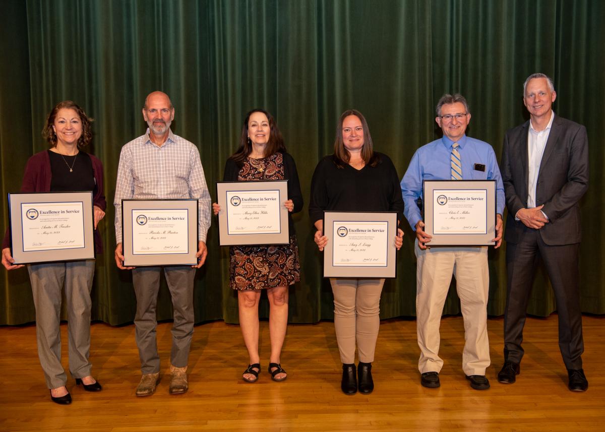Distinguished Staff Award honorees, (from left) Anita M. Tressler, Brooke M. Barton, Mary Ellen Hibbs, Amy S. Lingg and Chris E. Miller, stand with the president following an awards ceremony in the Klump Academic Center Auditorium.
