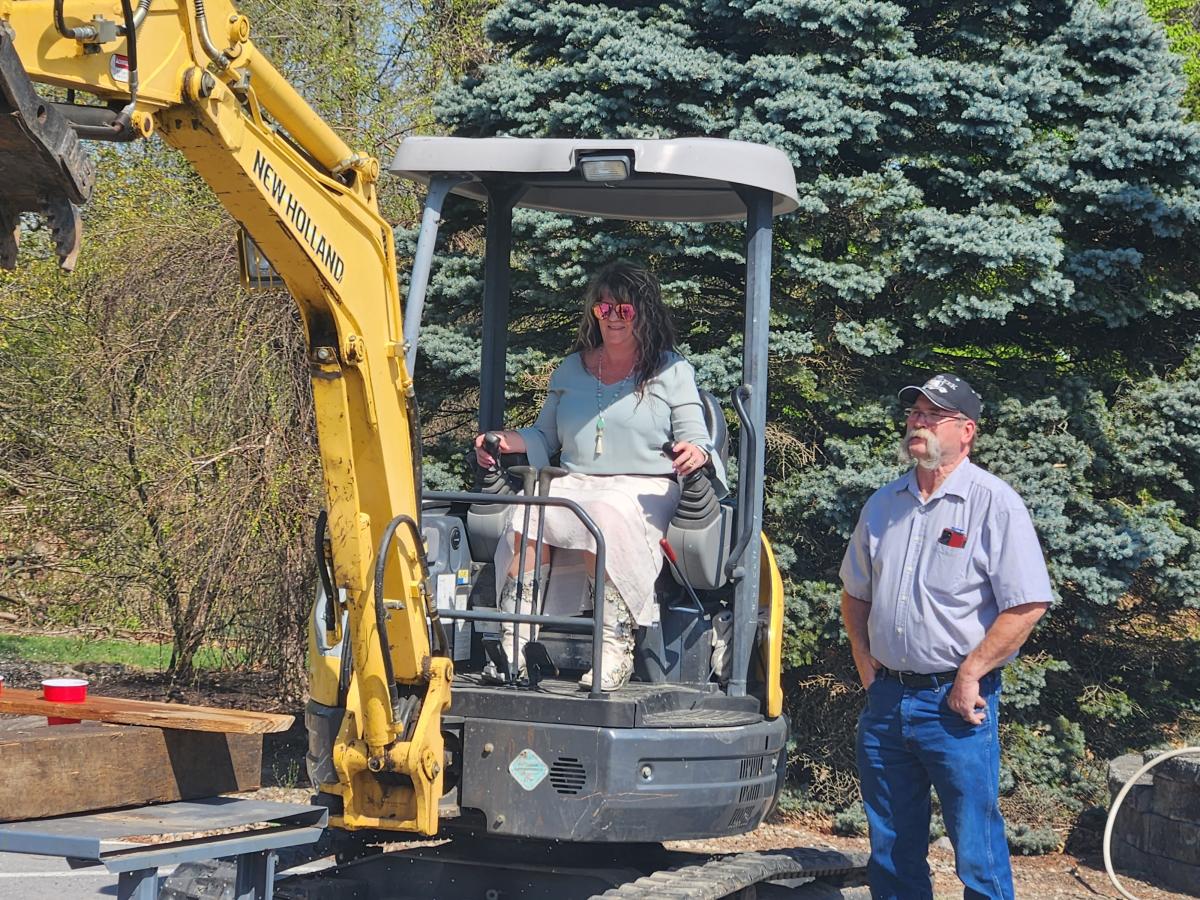 Under the trained eye of Kenneth J. Bashista, laboratory assistant for diesel equipment technology, Kimberly S. Cordrey takes the controls of a mini-excavator. Cordrey is the Lumley Aviation Center secretary.