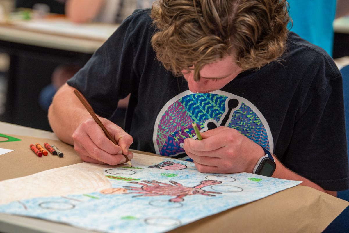 A young artist colorfully draws an under-the-sea scene in a graphic design session.