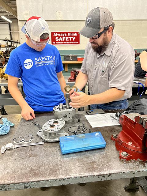 ... and getting their hands into a gear pump exercise in hydraulics, alongside faculty member Andy S. King.