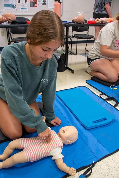 A participant performs CPR on an infant manikin.