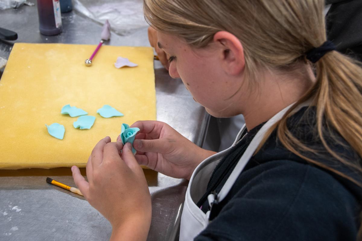 A participant carefully adds a gum-paste petal.