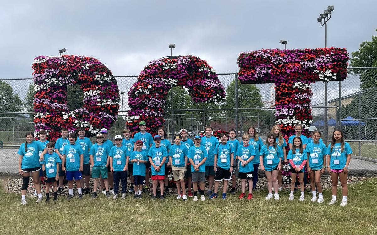 Wearing official camp T-shirts, the adventurous group assembles for a photo by the PCT floral backdrop on the west side of campus. (Photo by Laura M. Machak, coordinator of secondary partnership operations)