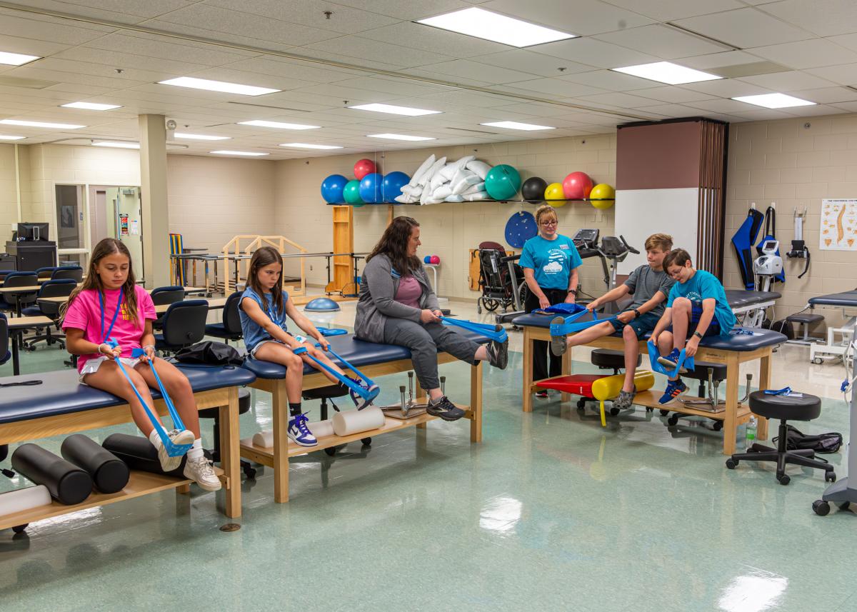 Part-time faculty member Sheryl E. Snyder-Everitt (seated at center) leads a real-world exercise in the physical therapist assistant lab. Standing is Barbara J. Stevens, office assistant to academic operations, among the faculty and staff who helped the camp run ever so smoothly all week.