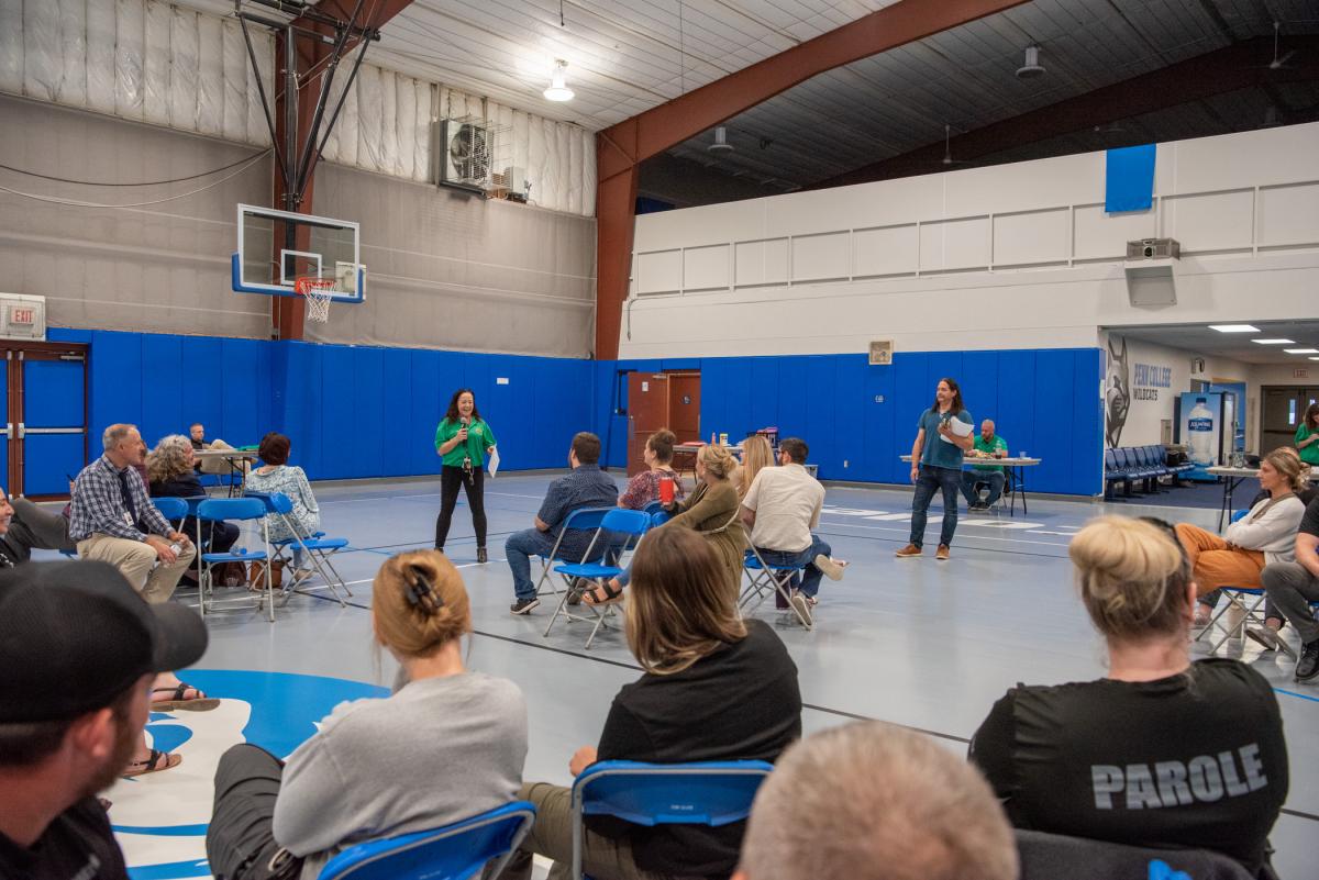 During the debrief, Sines (in green shirt with microphone) and Miller (standing at right), encourage participants to share their experiences. 