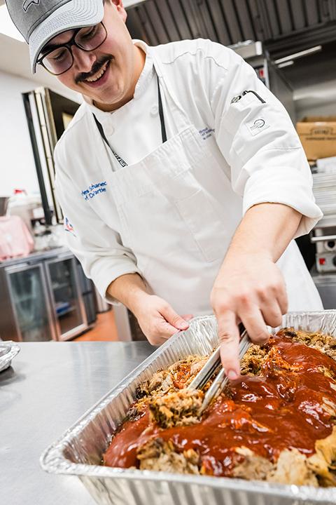Chef Charlie M. Suchanec, chef de partie in the college’s Le Jeune Chef Restaurant, stirs pulled pork. Suchanec is pursuing degrees in culinary arts technology and applied management.