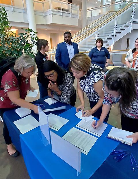 College employees take pens in hand to answer postcard inquiries from potential students.