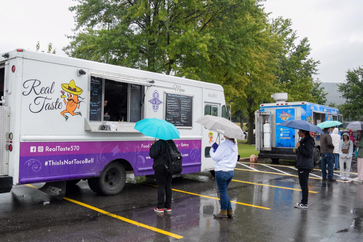 Patrons check out menus from Real Taste and The Mad Griller at the annual Food Truck Rally outside UPMC Field.