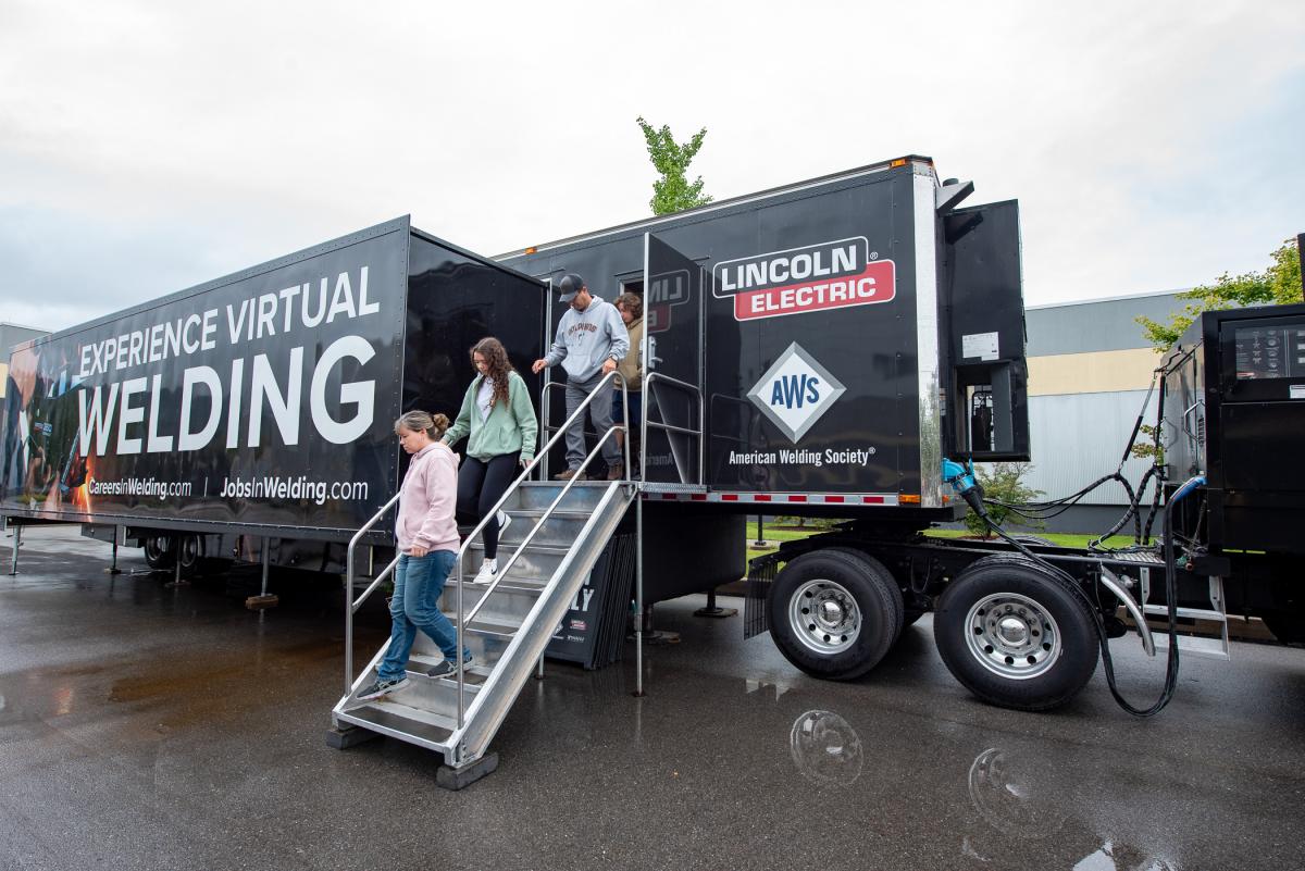 A family emerges from the American Welding Society’s virtual welding tractor-trailer, parked behind the college’s welding lab on Saturday.