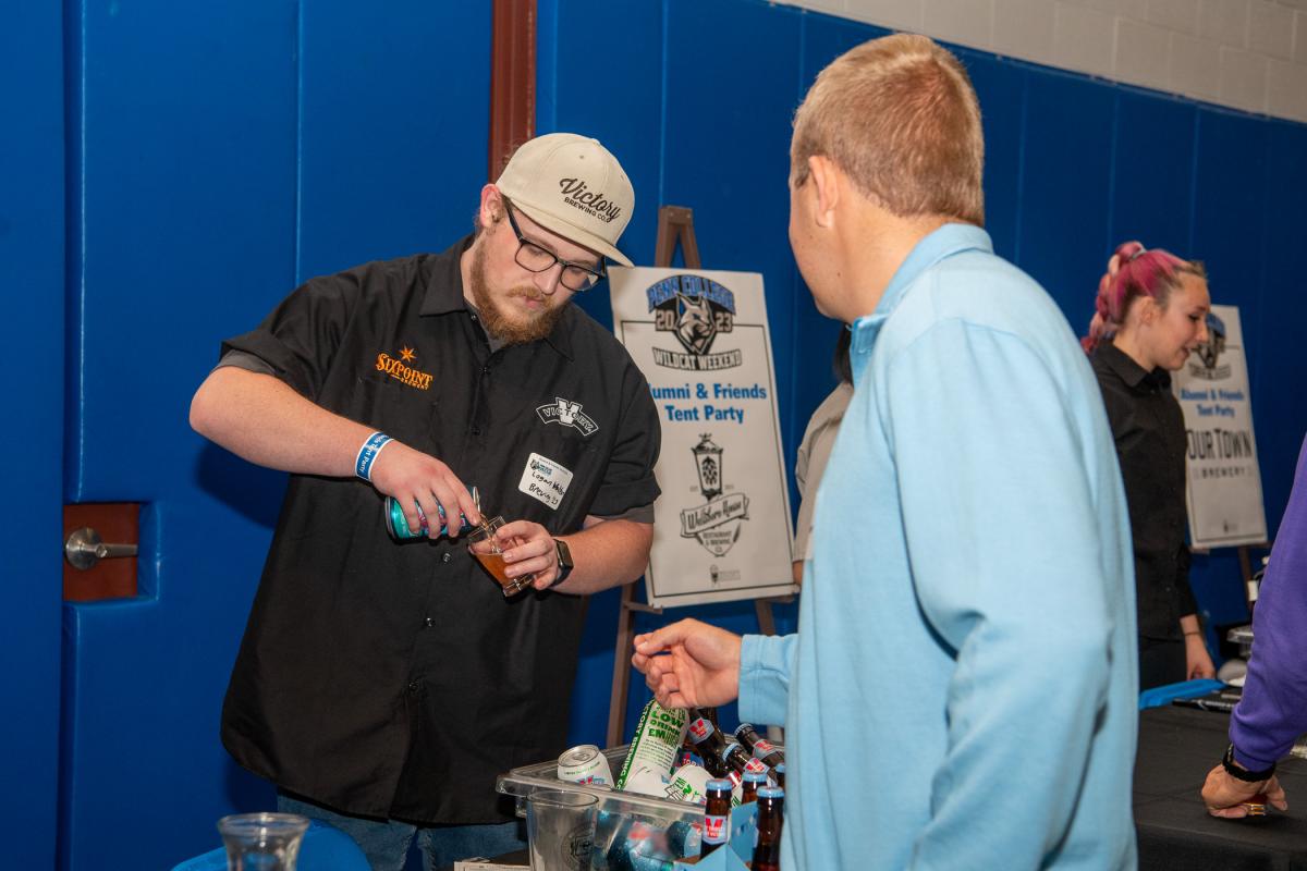 Victory brewer Logan M. Walton, ’23, brewing & fermentation science, offers up a tasty sample to a guest. 