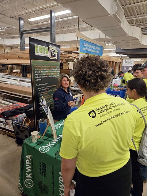 Stephanie Phillips-Taggart welcomes visitors to the Keystone Wood Products Association booth, set up in a campus carpentry lab.