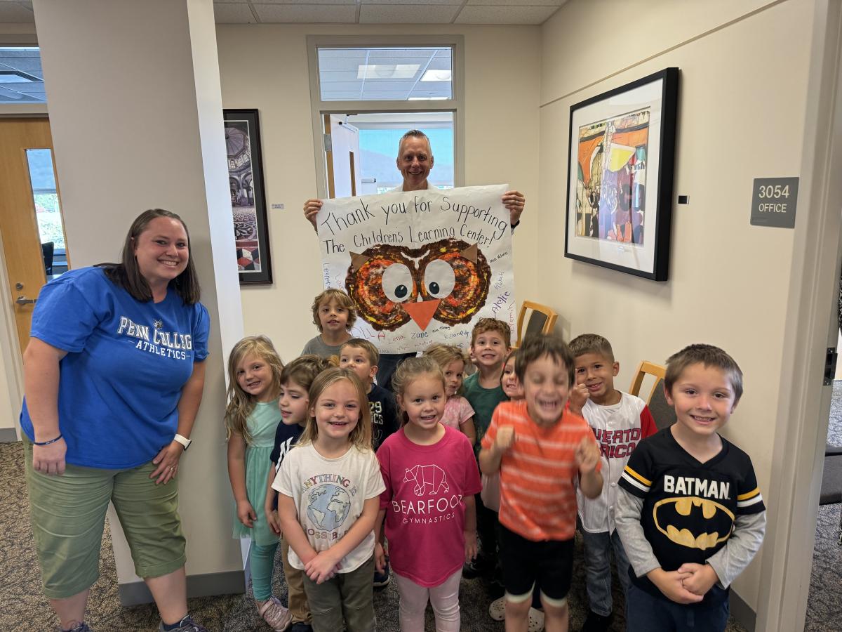 Penn College President Michael J. Reed proudly holds a "thank you" card hand-delivered by an enthusiastic flock of Birds. At left is Tiffany L. Tyhanic, childcare teacher at the Dunham Children's Learning Center.