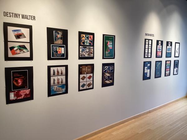 Graphic design projects on black matboard hanging on a white wall