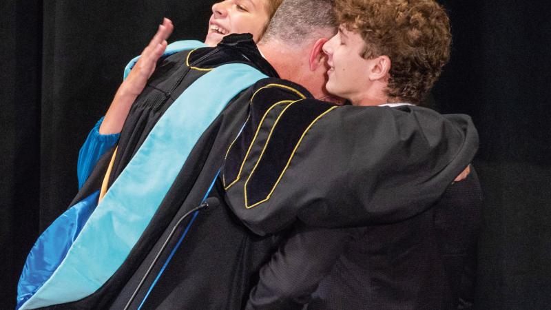 Reed hugs his teenage children, Cali and Gavin, after they surprised him by delivering speeches of their own at the ceremony.
