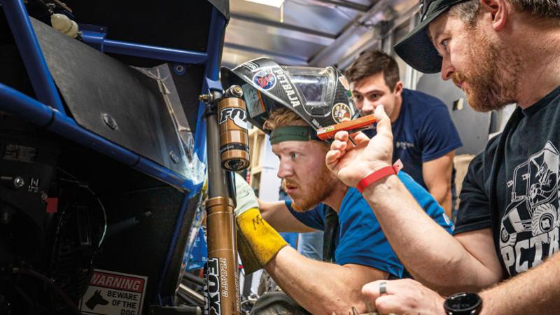 Inside the PCT Baja trailer, Fowler fixes a minuscule hole in the car's frame prior to technical inspection.