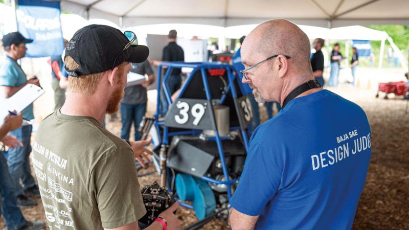 Team captain Marshall W. Fowler makes the case for the Penn College team's design. At right: Inside the PCT Baja trailer, Fowler fixes a minuscule hole in the car's frame prior to technical inspection.