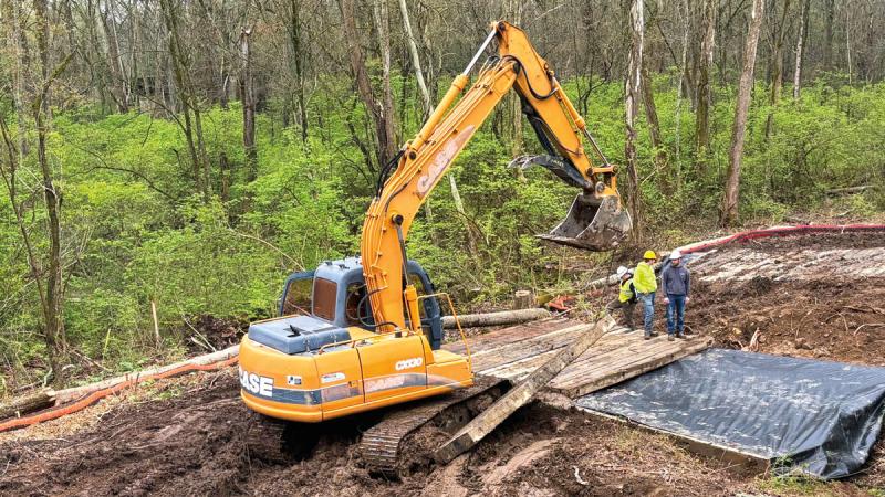 Students and faculty place timber mats to serve as a bridge over a crossing for the endurance course