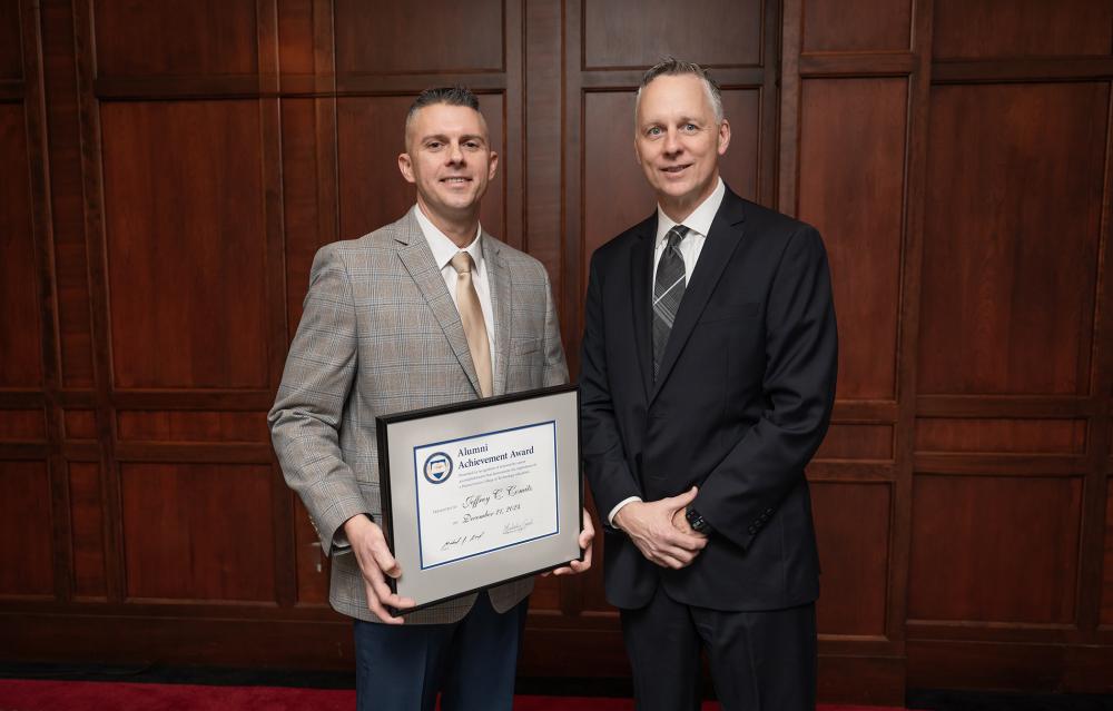 alumni award winner with plaque and college president