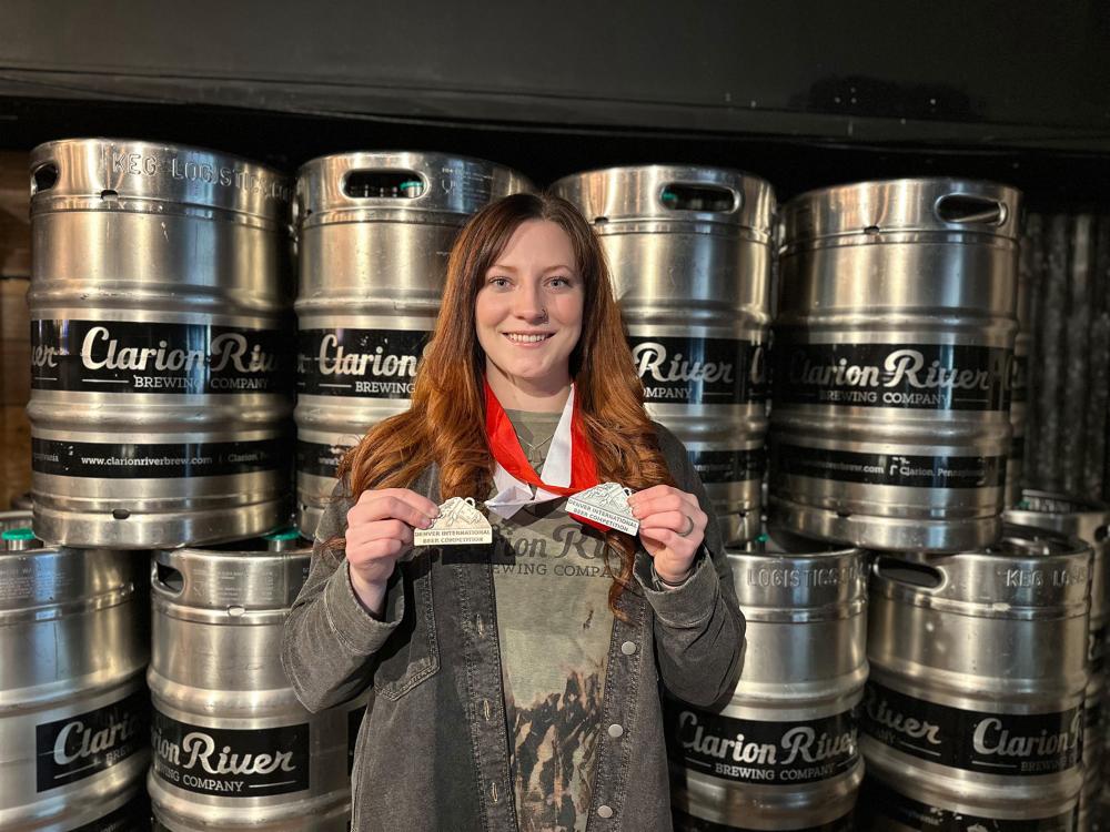 Smith holding two medals standing in front of beer kegs