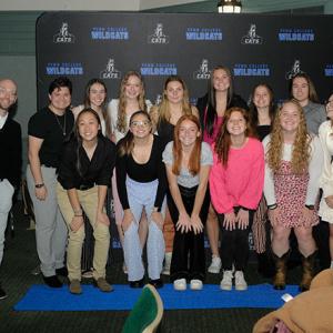 Coach Ian T. Scheller and his women's soccer team pause along the blue carpet for a group shot in tight quarters.