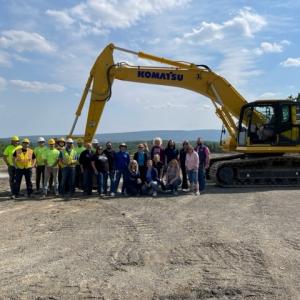 The group poses with a Komatsu excavator, just one of the pieces provided by corporate partners for students' instructional benefit.
