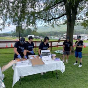 Wildcat baseball teammates (with coach Howard, at right) slice and serve pizza in South Williamsport. From left are Reptsik, Townsend, Bailor, Barbella and Gustkey.