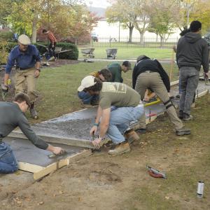 As students wield floats and a screed board, DiBucci (in blue shirt) supervises the busy crew.