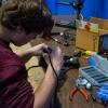 A competitor works on his 'bot at a well-stocked workbench.